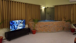 Une salle de bain avec une baignoire, un téléviseur et des plantes en pot.