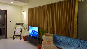Un salon avec une télévision, une plante en pot, une échelle et un mur recouvert de carreaux.