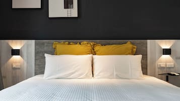Ein ordentlich bezogenes Bett mit weißen Leinen, einem Holzkopfschild und zwei Wandleuchten.
