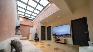 A modern living room with a high ceiling, a large TV, a sofa, a coffee machine, and a refrigerator. - yunhua bib (Hualien City)