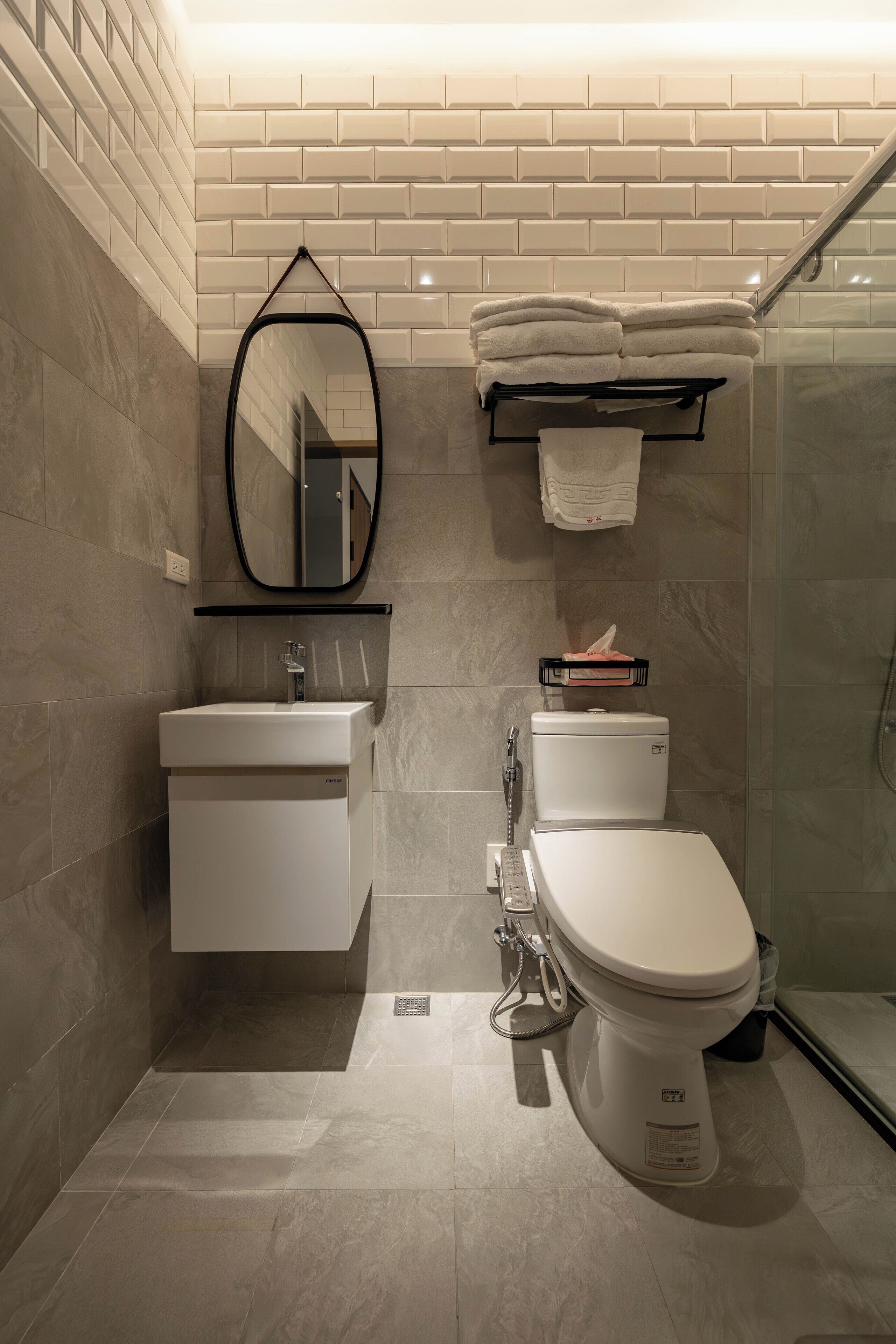 A modern bathroom with a white sink, toilet, and a glass shower enclosure.