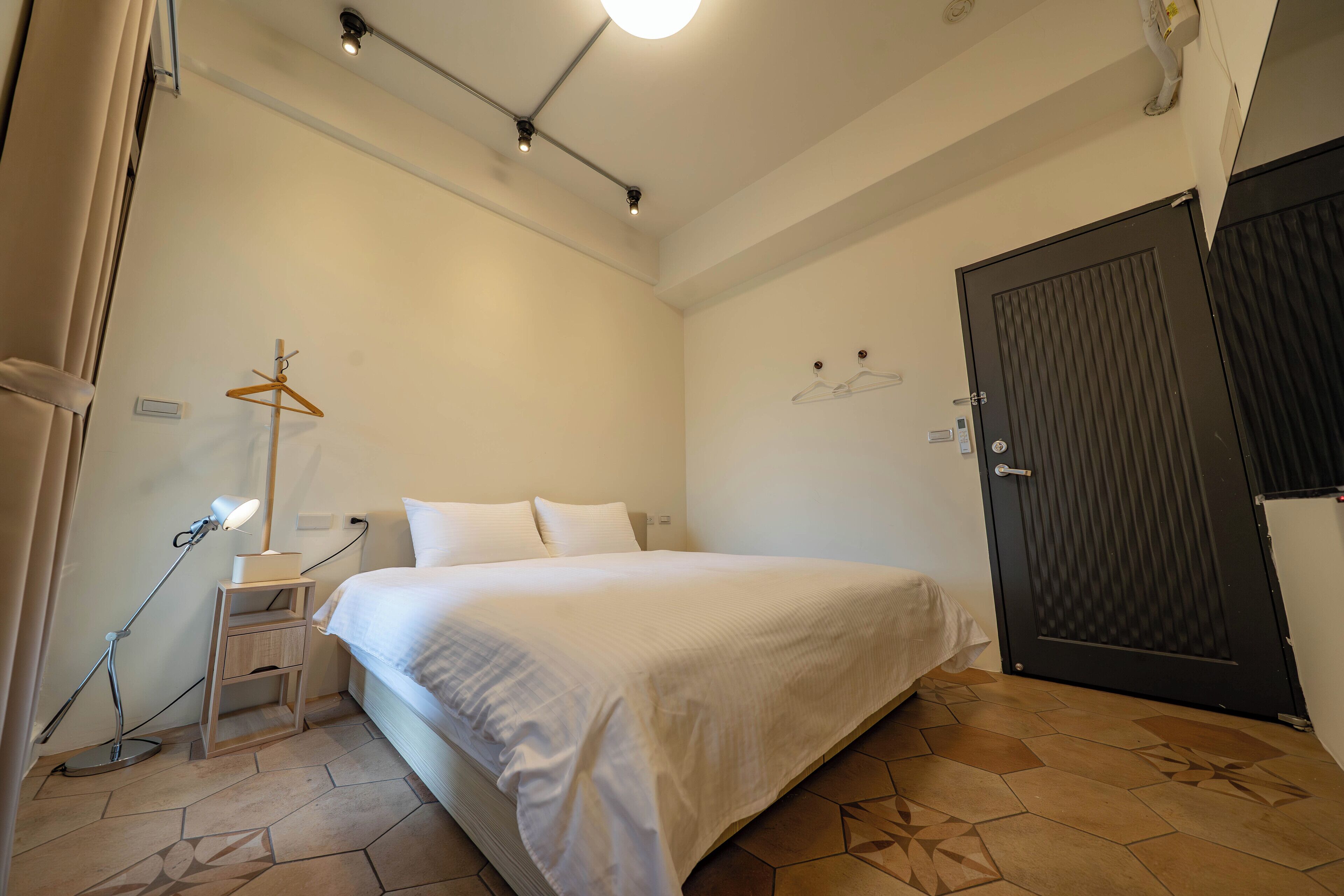 Un dormitorio con cama, mesita de noche, lámpara y armario.