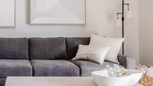 Un salon moderne avec un canapé gris, une table basse blanche et des livres.