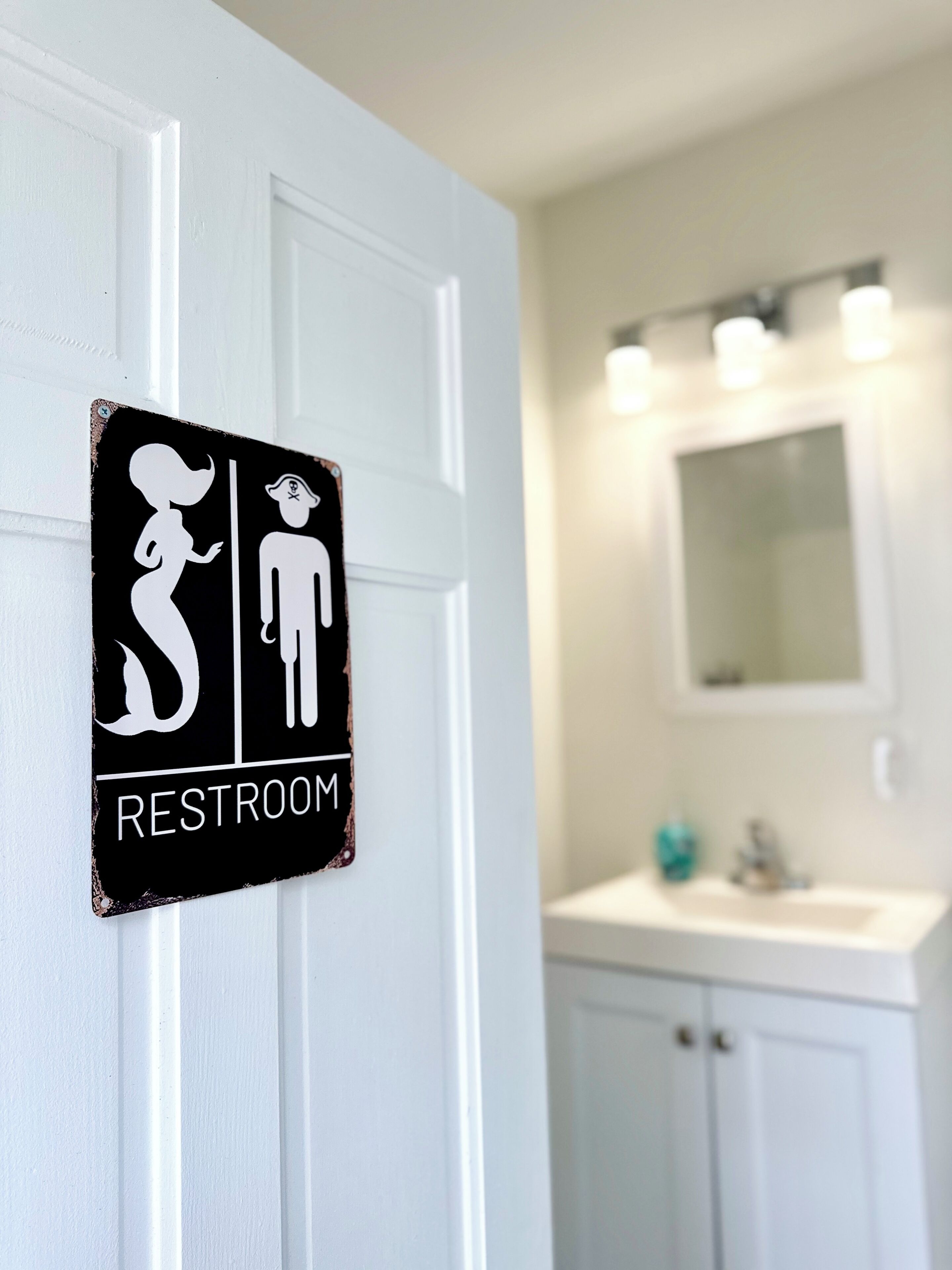 Een toiletbord met een afbeelding van een man en een vrouw, een wastafel en een spiegel op de achtergrond.