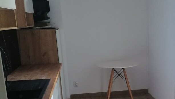 A small, open kitchen with a wooden countertop and a white table with wooden legs. - Hallera Wroclaw (Wrocław)