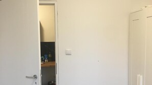 A room with a white door, a closet, and a shelf with various items. - Hallera Wroclaw (Wrocław)