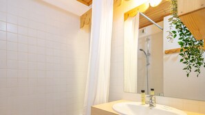 A bathroom with a bathtub, a sink with a mirror, and a shower. - Snug Apartment on the Mountains (Risoul)