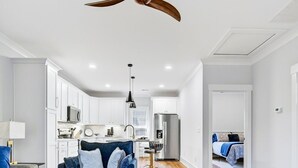 Een moderne woonkamer met een houten vloer, een blauwe zithoek en een plafondventilator.