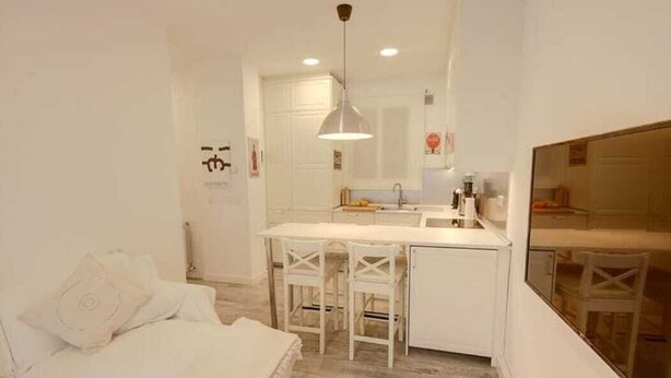 A compact room with a bed, a small kitchenette, and a dining area.