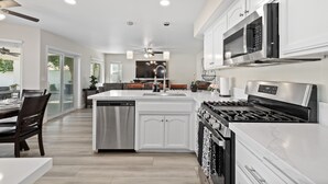 A modern kitchen with white cabinetry, stainless steel appliances, and a central island. - Casa Bella Gardens- Spacious 5-bedroom house in welcoming Bakersfield with Pool (Bakersfield)