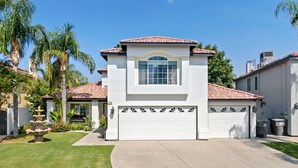 A two-story house with a white facade, a tiled roof, and a garage. - Casa Bella Gardens- Spacious 5-bedroom house in welcoming Bakersfield with Pool (Bakersfield)