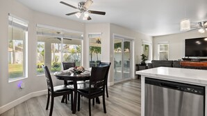 A modern kitchen with a central island, a dining area with a round table and chairs, and a ceiling fan. - Casa Bella Gardens- Spacious 5-bedroom house in welcoming Bakersfield with Pool (Bakersfield)