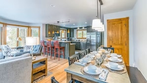 A modern kitchen with a central island, dining area with a long table set for six, and a cozy seating area with a sofa and chairs. - Tomboy Townhome-Curate Telluride, Near Market, Walk to Ski, Town, Modern (Telluride)