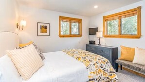 A bedroom with a bed, bedside tables, a TV, and two windows. - Tomboy Townhome-Curate Telluride, Near Market, Walk to Ski, Town, Modern (Telluride)
