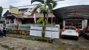 A residential area with a white car parked in front of a house with a corrugated metal roof. - OYO 94801 Pad Guest House (Bandung)