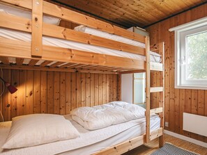 A bunk bed with a wooden frame, white bedding, and a window with a view of trees. - 4 Star Holiday Home in Hals (Hals)