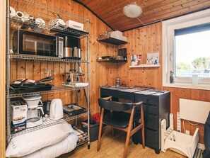 Una cocina con paredes de madera, un microondas, una cafetera y una estantería con servilletas de papel.