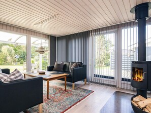 Una sala de estar moderna con un sofá negro, una mesa de centro de madera y un ventanal con cortinas.