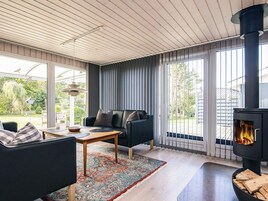 A modern living room with a black sofa, a wooden coffee table, and a large window with curtains.