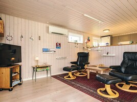 A living room with a television, two leather chairs, a small table, and a patterned rug.