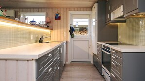 A modern kitchen with wooden paneling, a large island with a sink, and built-in appliances.