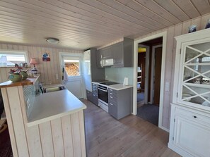 A kitchen with wooden cabinets, a microwave, and a sink. - 4 Star Holiday Home in Hals (Hals)