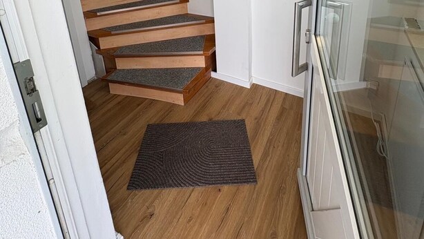 Eine Treppe mit Holzbodenstufen und einem dunklen Teppich am Fuß.