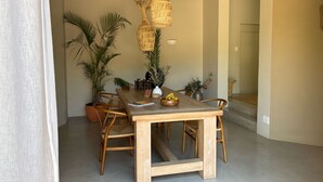 A dining area with a wooden table, wicker pendant lights, and potted plants. - Kokon Boutique Guesthouse (Cape Town)