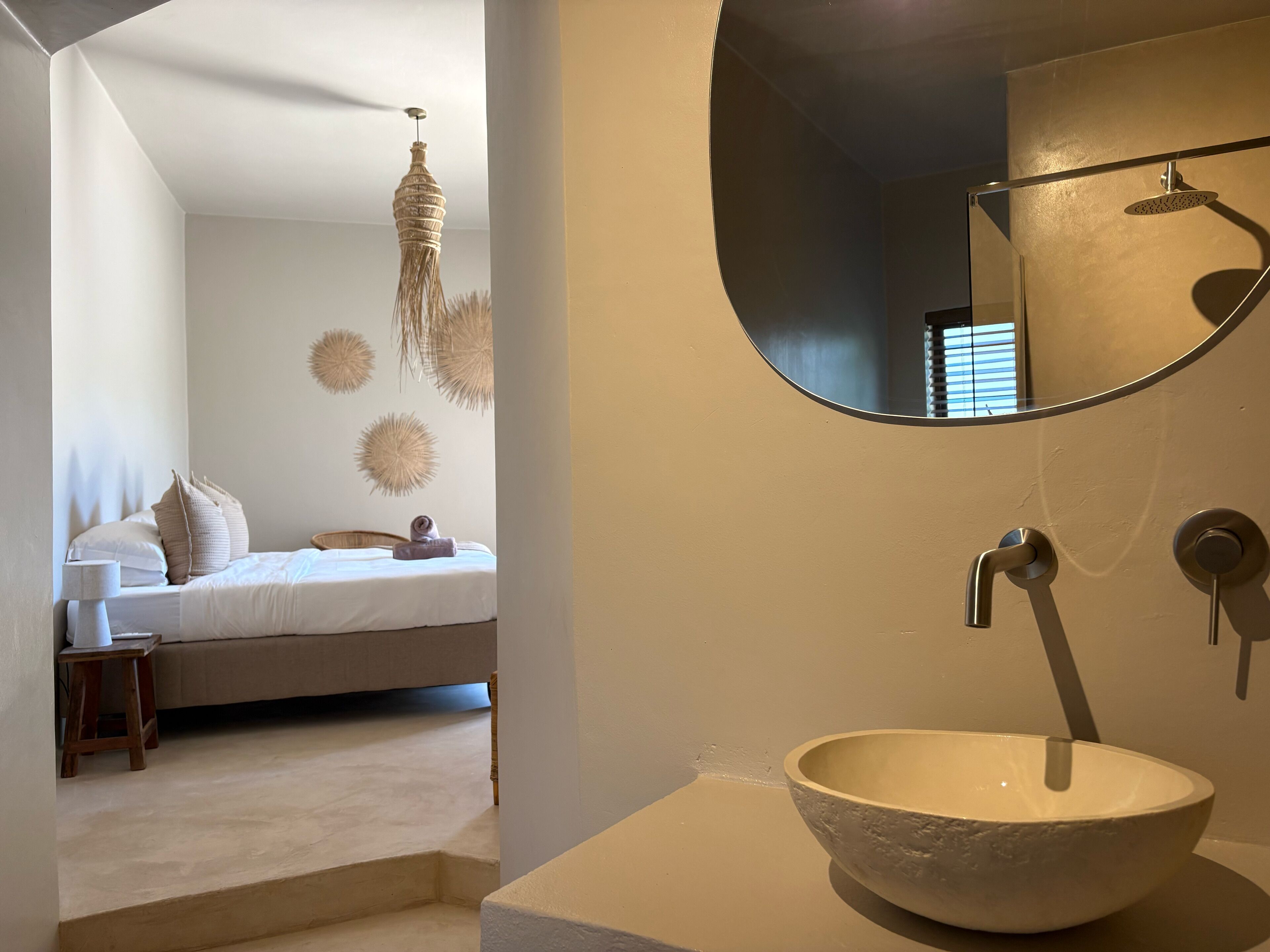 A bedroom with a bed, bedside table, and a hanging light fixture.