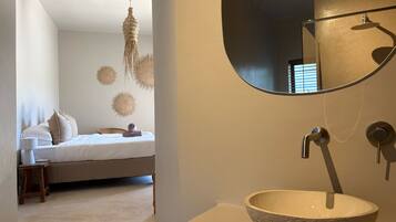 A bedroom with a bed, bedside table, and a hanging light fixture.