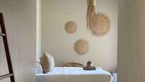 A bedroom with a bed, pillows, a woven wall hanging, and a small table. - Kokon Boutique Guesthouse (Cape Town)