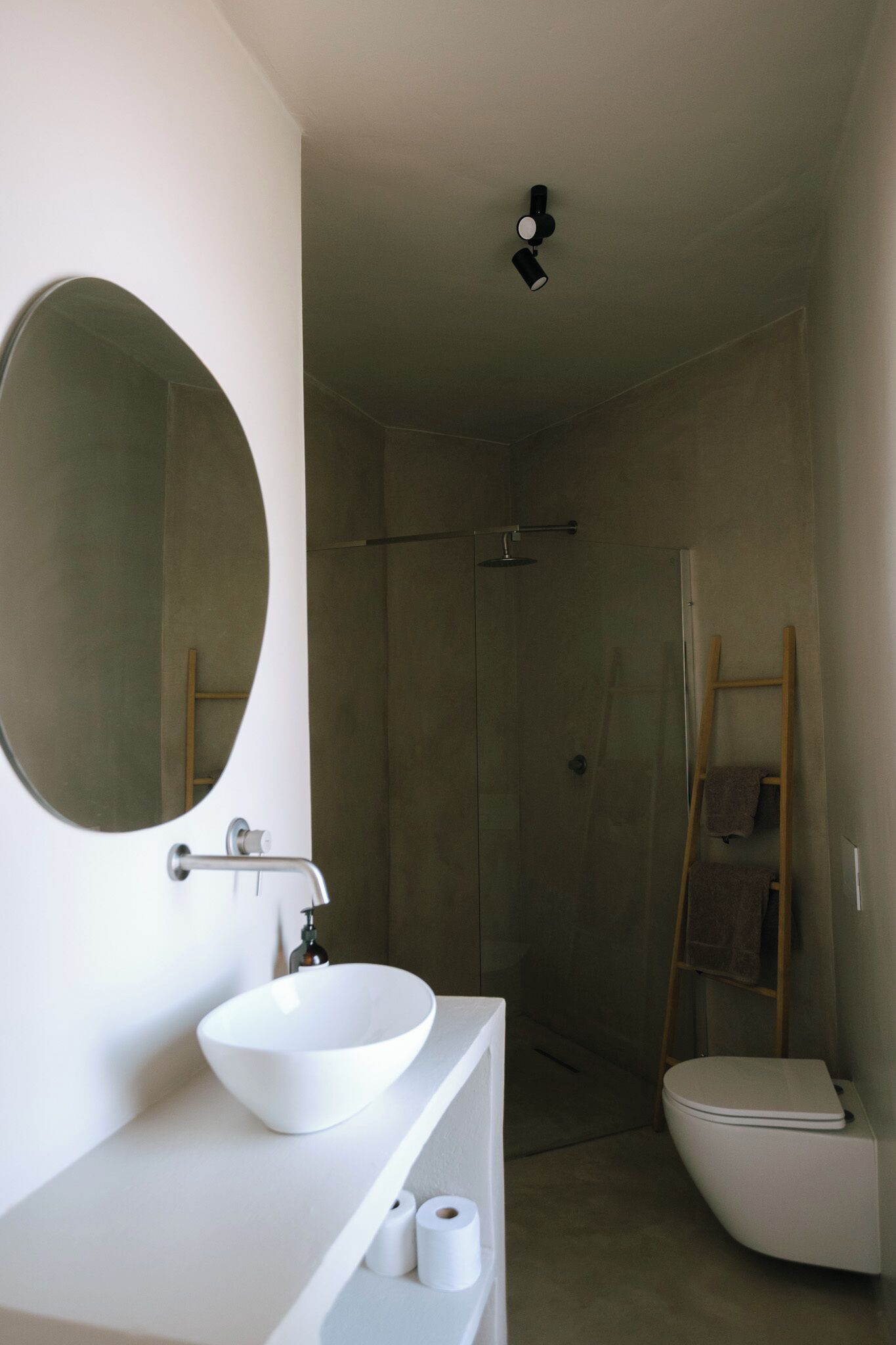 A modern bathroom with a white sink, mirror, and toilet.