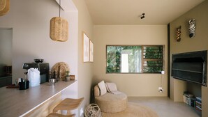 A modern kitchen with a bar area, a round seating area, and a large window with a view of greenery. - Kokon Boutique Guesthouse (Cape Town)