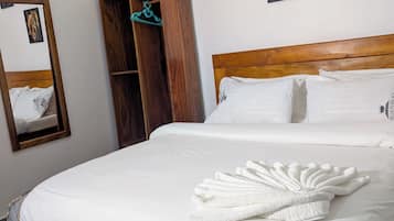 Un lit bien fait, avec une couette blanche et une serviette décorative.