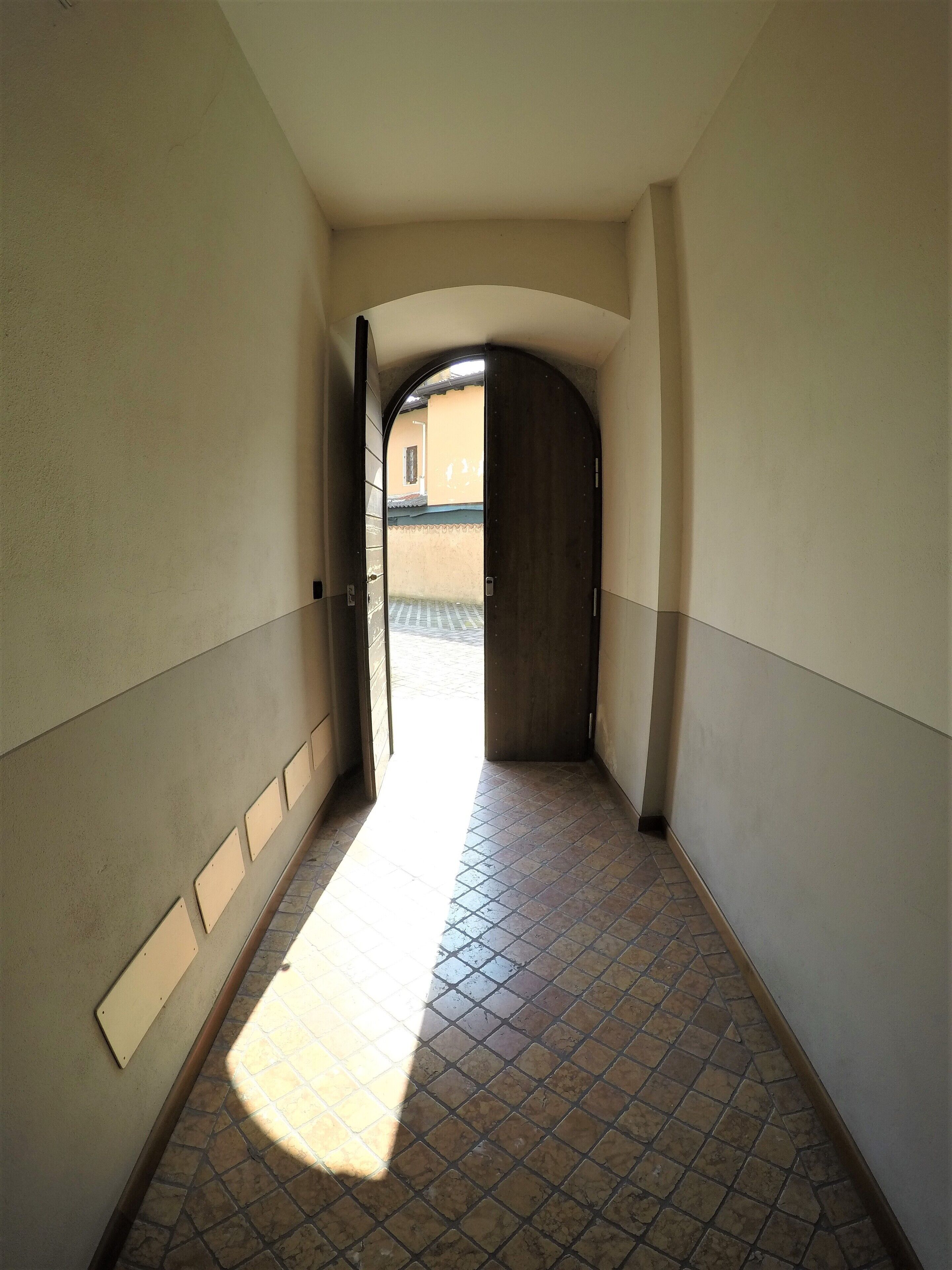 A narrow hallway with tiled flooring and a door leading to an outdoor area.