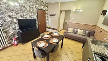 Un salon moderne comprenant un coin repas, un canapé, un téléviseur et une cuisine équipée d’une cuisinière.