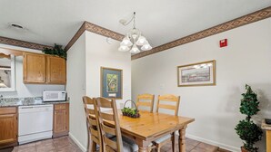 A dining area with a wooden table and chairs, a microwave, and a ceiling light fixture. - One Bedroom, One Bath Condo in Pigeon Forge, City View,  A couple's getaway (Pigeon Forge)