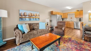 A living room with a brown leather sofa, a wooden coffee table, and a colorful rug.