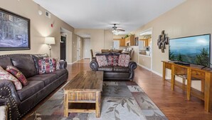 A living room with a sofa, a coffee table, a TV, and a dining area in the background. - Two bedroom, two bath condo| Pigeon Forge| City View (Pigeon Forge)