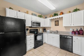 A kitchen with white cabinets, a black refrigerator, a microwave, an oven, and a dishwasher. - One bedroom, one bathroom Condo| First Floor| Pigeon Forge| Sleeps 4 (Pigeon Forge)