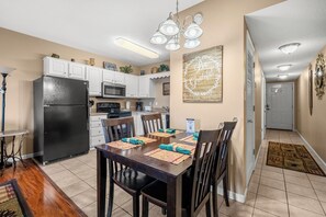 A kitchen with white cabinets, a black refrigerator, and a dining table set with placemats and chairs. - One bedroom, one bathroom Condo| First Floor| Pigeon Forge| Sleeps 4 (Pigeon Forge)