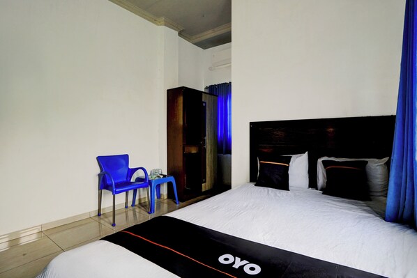 Una habitación de hotel con una cama, una silla azul, una mesita y un armario.