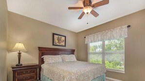A bedroom with a bed, a nightstand, a lamp, a ceiling fan, a window with blinds, and a framed picture on the wall. - Three bedroom, three bath condo| Pigeon Forge| Close to Dollywood| Sleeps 8 (Pigeon Forge)