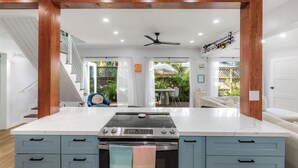 Una cucina moderna con un'isola grande, forno integrato e ventilatore a soffitto.