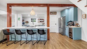 Una cucina moderna con isola centrale, sgabelli da bar e pensili azzurri.