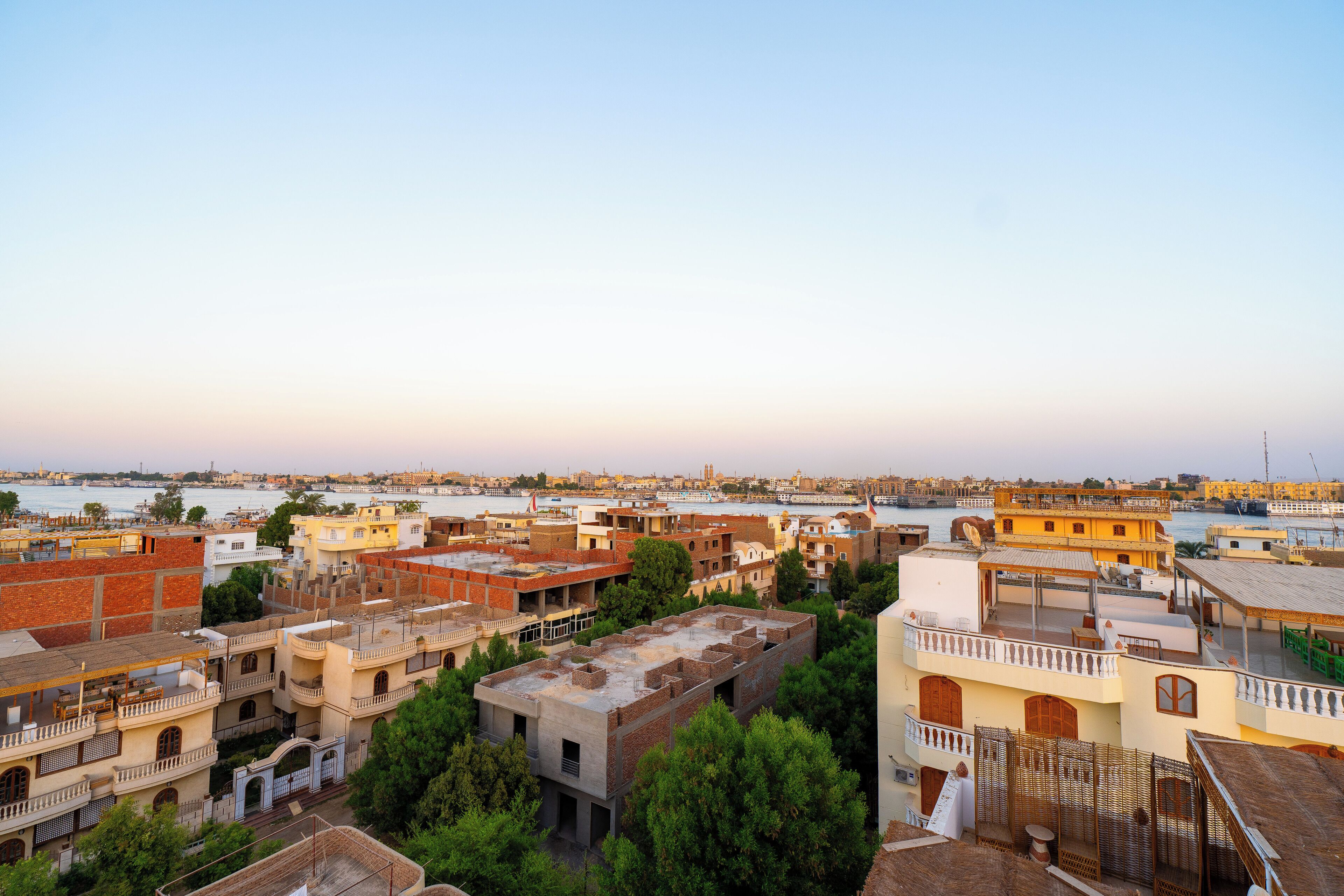 Une vue urbaine avec une rivière en arrière-plan, où l’on peut voir un mélange de bâtiments traditionnels et modernes.