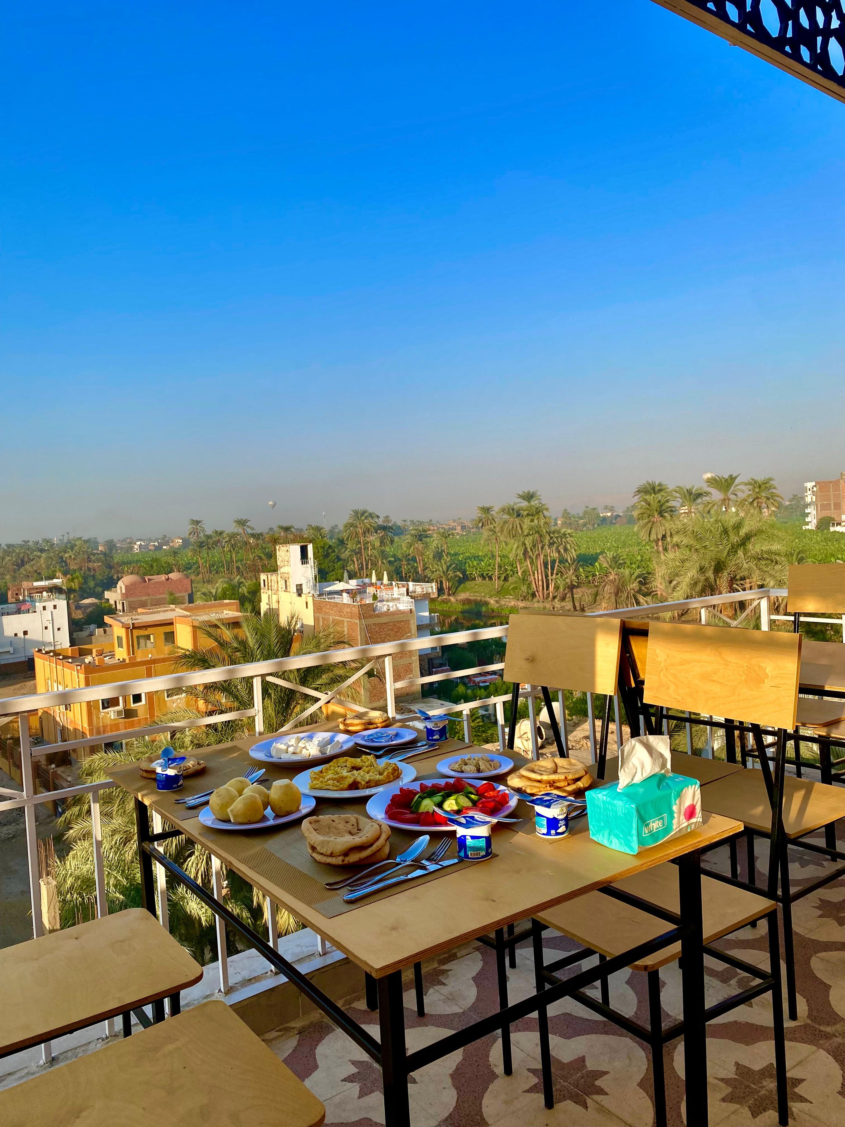 Comedor con una mesa dispuesta para una comida, con vistas a un paisaje urbano con edificios y palmeras.