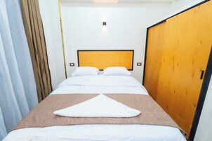 Una habitación de hotel con una cama, un armario de madera y una cortina.