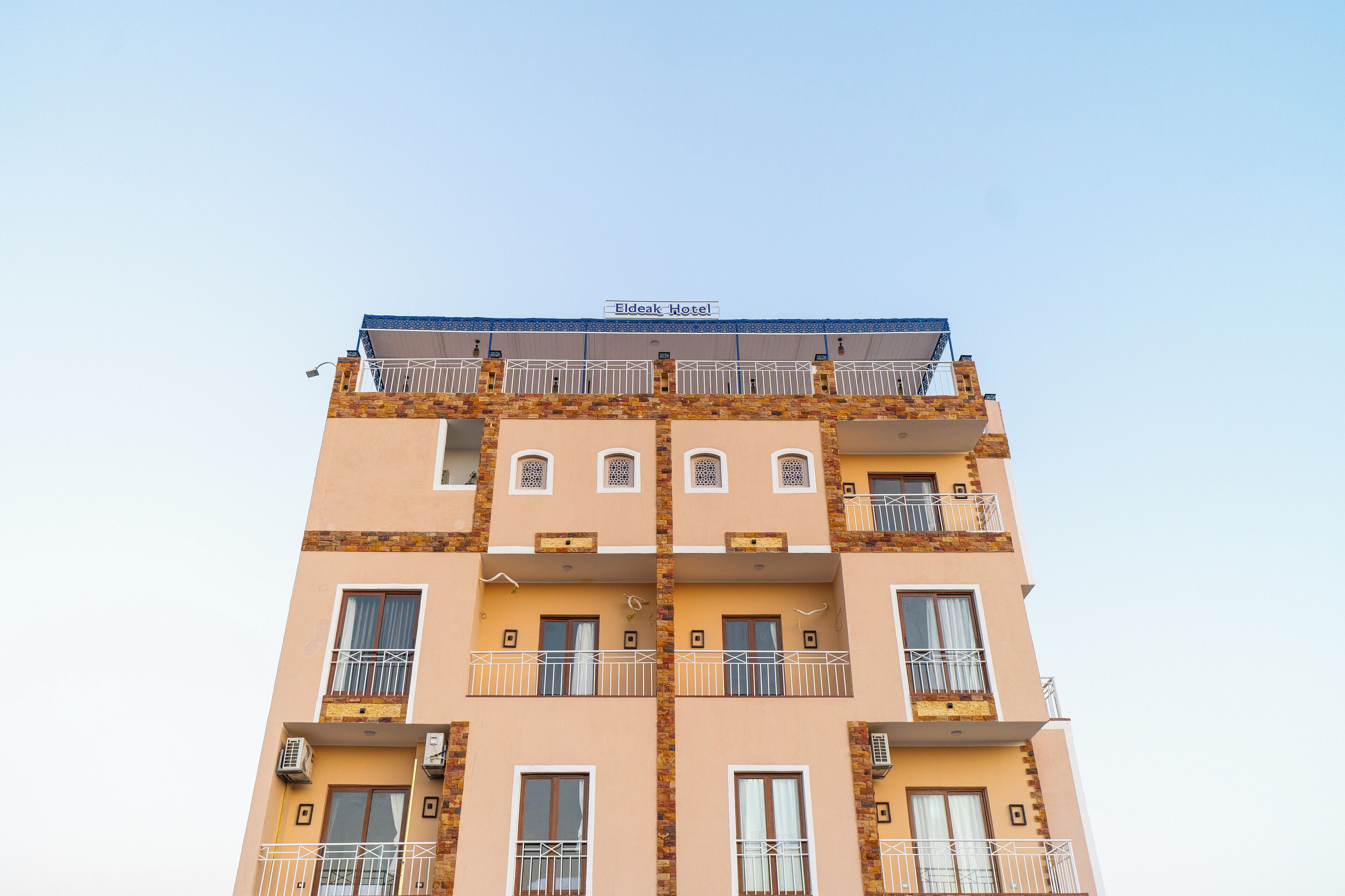Un hôtel à plusieurs étages, doté de balcons et de climatiseurs.