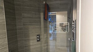 Une salle de bain moderne équipée de toilettes, d’une douche à parois de verre et d’un porte-serviettes.